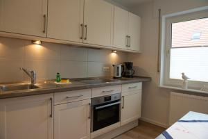 a kitchen with white cabinets and a sink and a window at Olivia in Norden