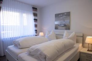 a bedroom with two beds with white sheets and a window at Olivia in Norden +4 photos