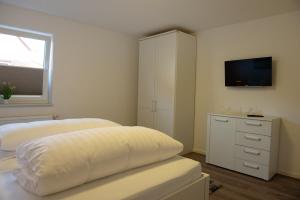 a bedroom with a bed and a dresser with a television at Deichnähe - G in Norddeich