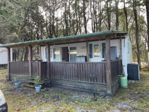 ein kleines Haus mit einer Veranda und einem Zaun in der Unterkunft Bungalow tout confort in Hourtin