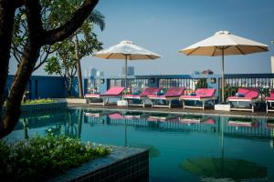 a swimming pool with chairs and umbrellas at The Frangipani Royal Palace Hotel in Phnom Penh