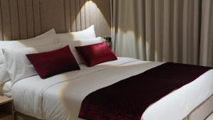 a large bed with two red pillows on it at Suites El Ghailani in Dakhla
