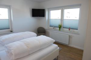 two white beds in a room with windows at Mole links in Norddeich