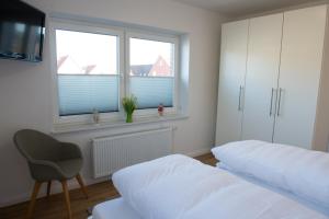 a bedroom with two beds and a chair and two windows at Mole links in Norddeich