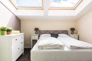 a bedroom with a white bed with a skylight at Wildgrün Panorama Lodge 8b in Pfronten