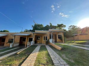 a small yellow house with a brick driveway at Villa Jr 3 near the peñon guacalillo in Tarcoles