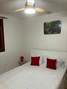 a white bed with two red pillows on it at La Maison d 'Hippolyte in Vieux-Habitants