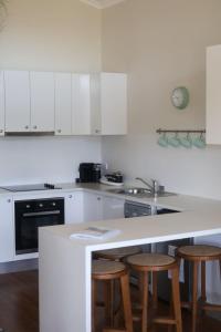 Una cocina con gabinetes blancos y una encimera con taburetes. en Mortimer's Wines Loft - Adults Only Retreat, en Orange 19 fotos más