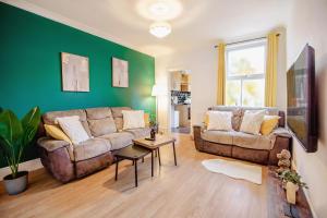 ein Wohnzimmer mit 2 Sofas und einer grünen Wand in der Unterkunft Central Urban Retreat Oasis Free Parking 13ppl in Sheffield