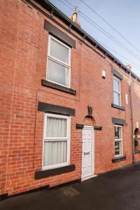 ein rotes Backsteingebäude mit zwei Fenstern und einer weißen Tür in der Unterkunft Central Urban Retreat Oasis Free Parking 13ppl in Sheffield