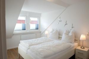 a white bed in a room with two windows at Mole rechts in Norden +3 photos
