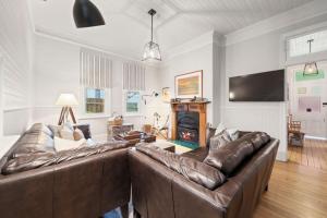 sala de estar con sofá de cuero y chimenea en Brechin Cottage, en Blackheath