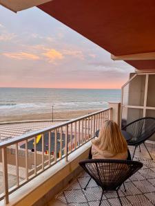 una mujer sentada en una silla en un balcón con vistas a la playa en Casa Palmera, en Sueca 19 fotos más