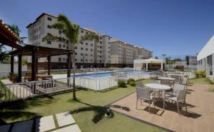 a patio with a table and chairs and a pool at Apartamento Ilhéus in Ilhéus