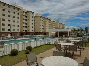 a hotel patio with tables and chairs next to a pool at Apartamento Ilhéus in Ilhéus