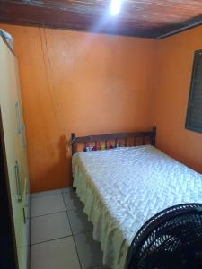 a bed in a room with an orange wall at Residência do Roberto in Rosário do Sul