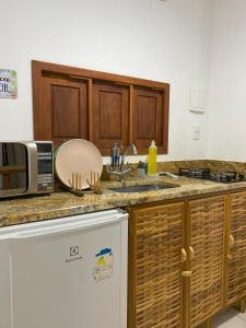a kitchen with a sink and a microwave at Loft Reserva Sapiranga Praia do Forte Vila Hen 102 in Mata de Sao Joao
