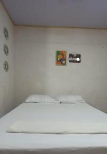 a white bed in a room with a camera on the wall at Hostal Brisas del Ometepe Habitación 3 in Rivas