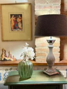 a lamp and a vase with flowers on a table at Luxury Deco Painter Ca' Dottori Perugia in Perugia
