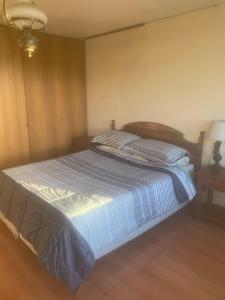 a bedroom with a bed with a blue comforter at Hostal Edificio Kuramochi in Temuco