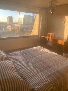 a bed in a room with a large window at Hospedaje Edificio Kuramochi in Temuco