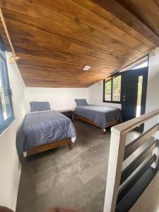 a bedroom with two beds and a wooden ceiling at Cabañas lindo amanecer in Huasca de Ocampo