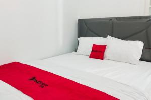 a bed with a red blanket and white pillows at RedDoorz at Jalan Terusan Ryacudu near Exit Tol Kotabaru Lampung in Kedaton