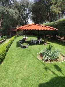 Los AranaにあるHospedajeRancholajoya-Habitacion Fresnoの庭のオレンジ色の屋根のガゼボ(テーブル、椅子付)