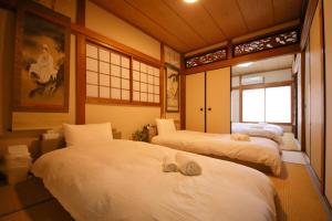 ein Schlafzimmer mit 3 Betten und Handtüchern darauf in der Unterkunft おまつりハウス in Osaka