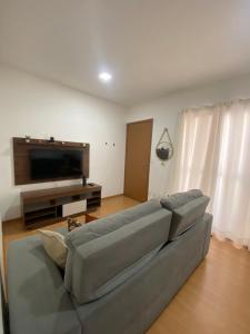 a living room with a couch and a flat screen tv at Apartamento Praia de Ponta com dois quartos in Natal