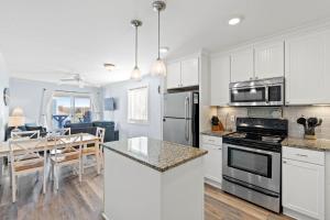a kitchen and dining room with white cabinets and a table at I'll Be There For You in Ocean Isle Beach