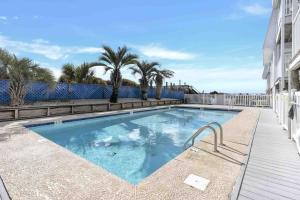 a swimming pool with palm trees and a fence at I'll Be There For You in Ocean Isle Beach