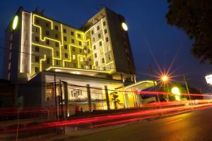 泗水的住宿－耶穆爾薩利黃釉酒店，街道前有 ⁇ 虹灯的建筑