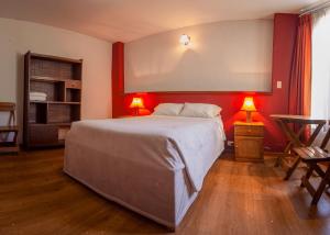 a bedroom with a large bed with red walls and two lamps at La Compañía de Jerusalen in Arequipa