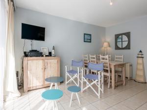 een woonkamer met een tafel, stoelen en een televisie bij Apartment in Koksijde near the Sea in Koksijde