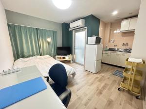 a room with a bed and a kitchen with a refrigerator at SABBATH uzumasa 201 in Kyoto