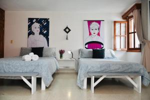 two beds in a room with posters on the wall at Casa Nazimova Indigo Room in San Cristóbal de Las Casas