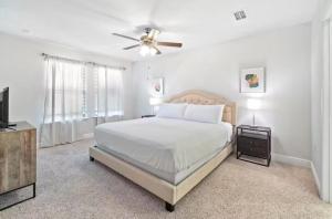 a white bedroom with a bed and a ceiling fan at Pensacola Paradise Downtown in Pensacola