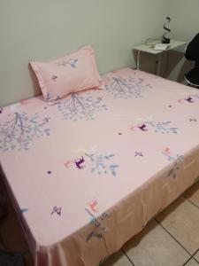 a bed with a pink blanket with flowers on it at A room in a quiet place in Pretoria