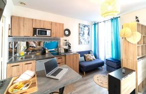 una cucina e un soggiorno con un computer portatile sul tavolo di Appart moderne REVE BLEU Hypercentre Blois à 5 min Château a Blois Altre 19 foto