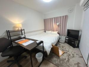a small bedroom with a bed and a desk with a computer at SABBATH uzumasa 101 in Kyoto