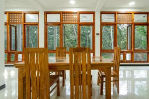 a dining room with a wooden table and windows at Diyaluma NAS Villa in Koslanda +21 photos