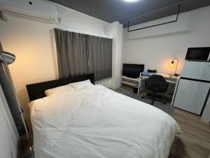 a bedroom with a large white bed and a desk at SABBATH uzumasa 102 in Kyoto