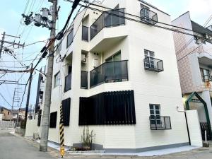 a white building with black windows on a street at SABBATH uzumasa 102 in Kyoto