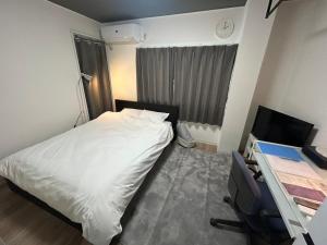 a bedroom with a bed and a desk with a computer at SABBATH uzumasa 102 in Kyoto