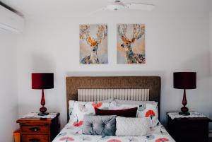 a bedroom with a bed with two lamps and two paintings at Glenview Alpaca Farm in Yass