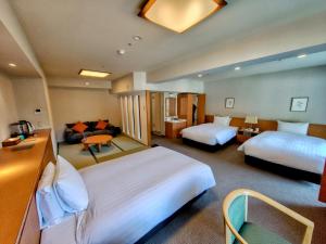 a hotel room with two beds and a couch at Yumoto Fujiya Hotel in Hakone