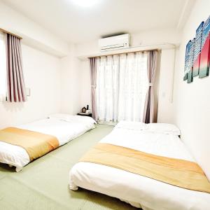 deux lits dans une chambre blanche avec une fenêtre dans l'établissement LuckyHouse浅草 成田羽田直行, à Tokyo
