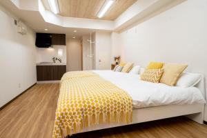 una camera da letto con un letto bianco con una coperta gialla di Tookin house 池袋 a Tokyo