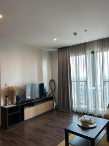 a living room with a tv and a couch and a table at BTS Bearing 23Fl 68sqm condo with open city view Shared rooftop and gym in Samut Prakan